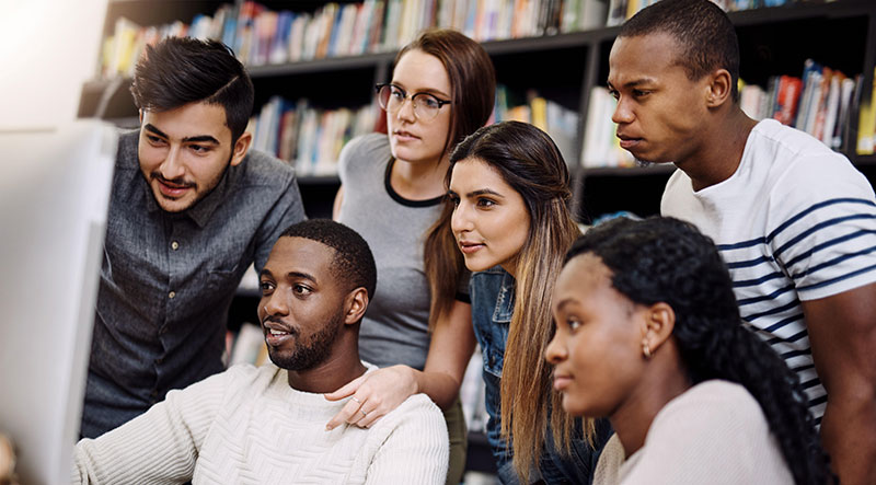 Group of students gather around a computer